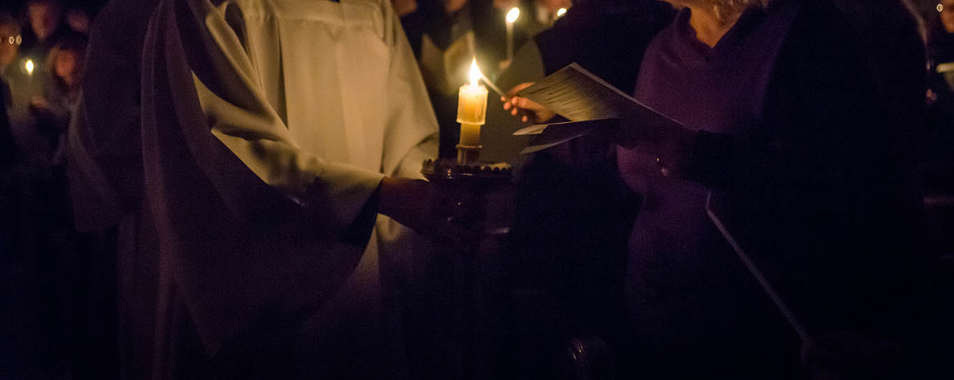 A server lighting a parishioner's candle at a previous Advent Carol Service