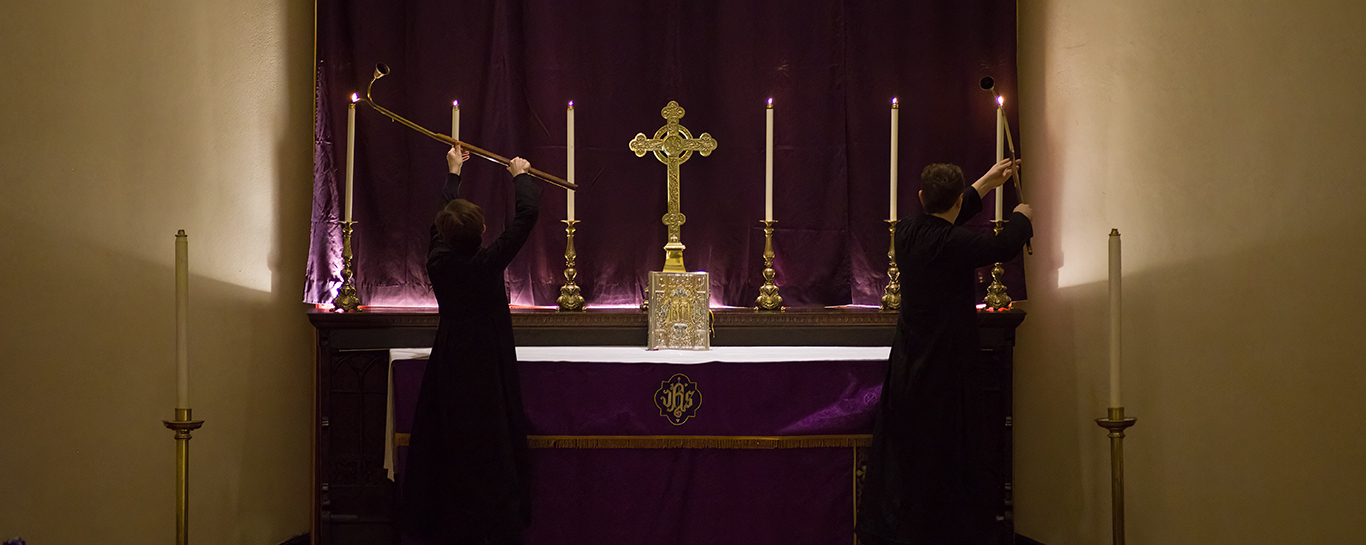 Two servers light altar candles during the first Sunday in Advent, 2025