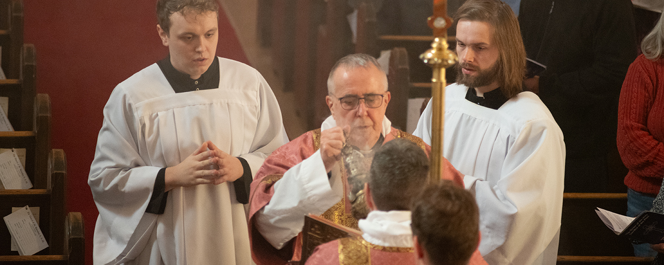 Fr Tudin censing the gospel book before a gospel reading