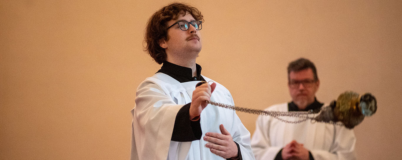 A thurifer censing the congregation