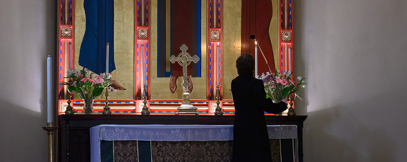 A server lights an altar candle during the fifth Sunday of Trinity