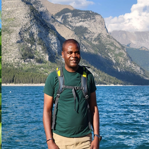 Fr Kwari posing beside Lake Minniwanka in hiking garb.