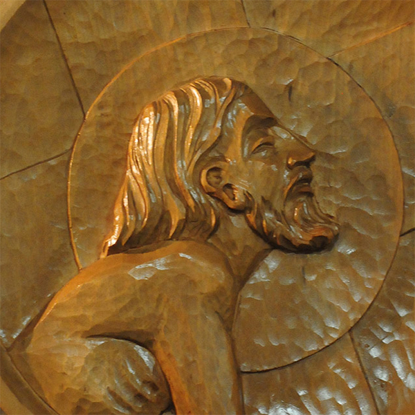 One of the stations of the cross: a wood relief carving of Christ bearing the cross